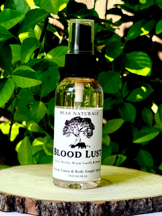 A clear bottle with a black fingertip style spray nozzle featuring a white label with black writing on a wooden surface with green leaves in the background.