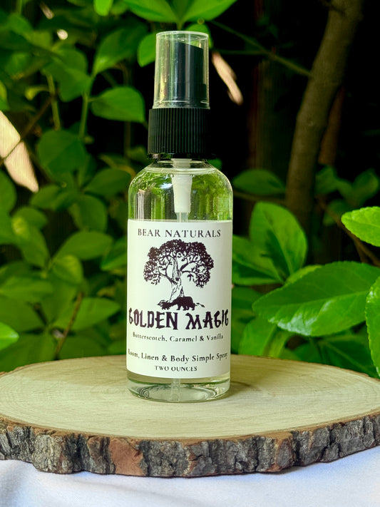 A clear bottle with a black fingertip style spray nozzle featuring a white label with black writing on a wooden surface with green leaves in the background.