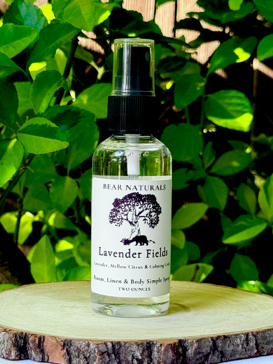 A clear bottle with a black fingertip style spray nozzle featuring a white label with black writing on a wooden surface with green leaves in the background.