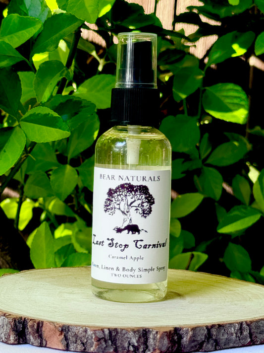 A clear bottle with a black fingertip style spray nozzle featuring a white label with black writing on a wooden surface with green leaves in the background.